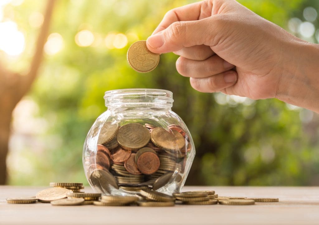 Person Placing Coins in Jar Learning About Gas Line Repair Cost