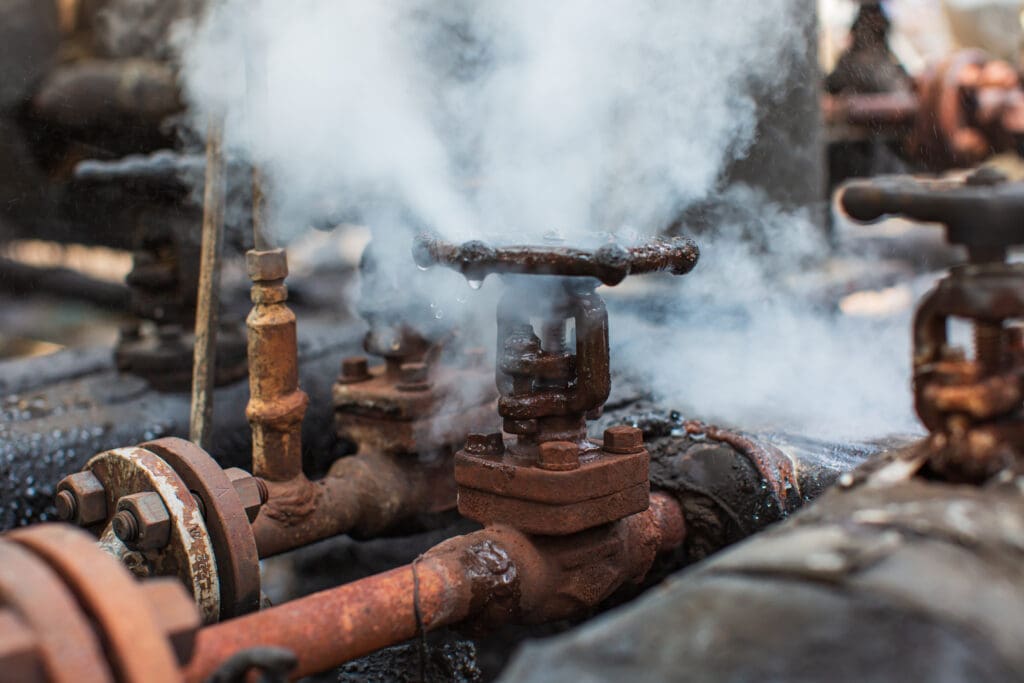 Leaking pressure relief valve with steam release and corrosion in an industrial system.